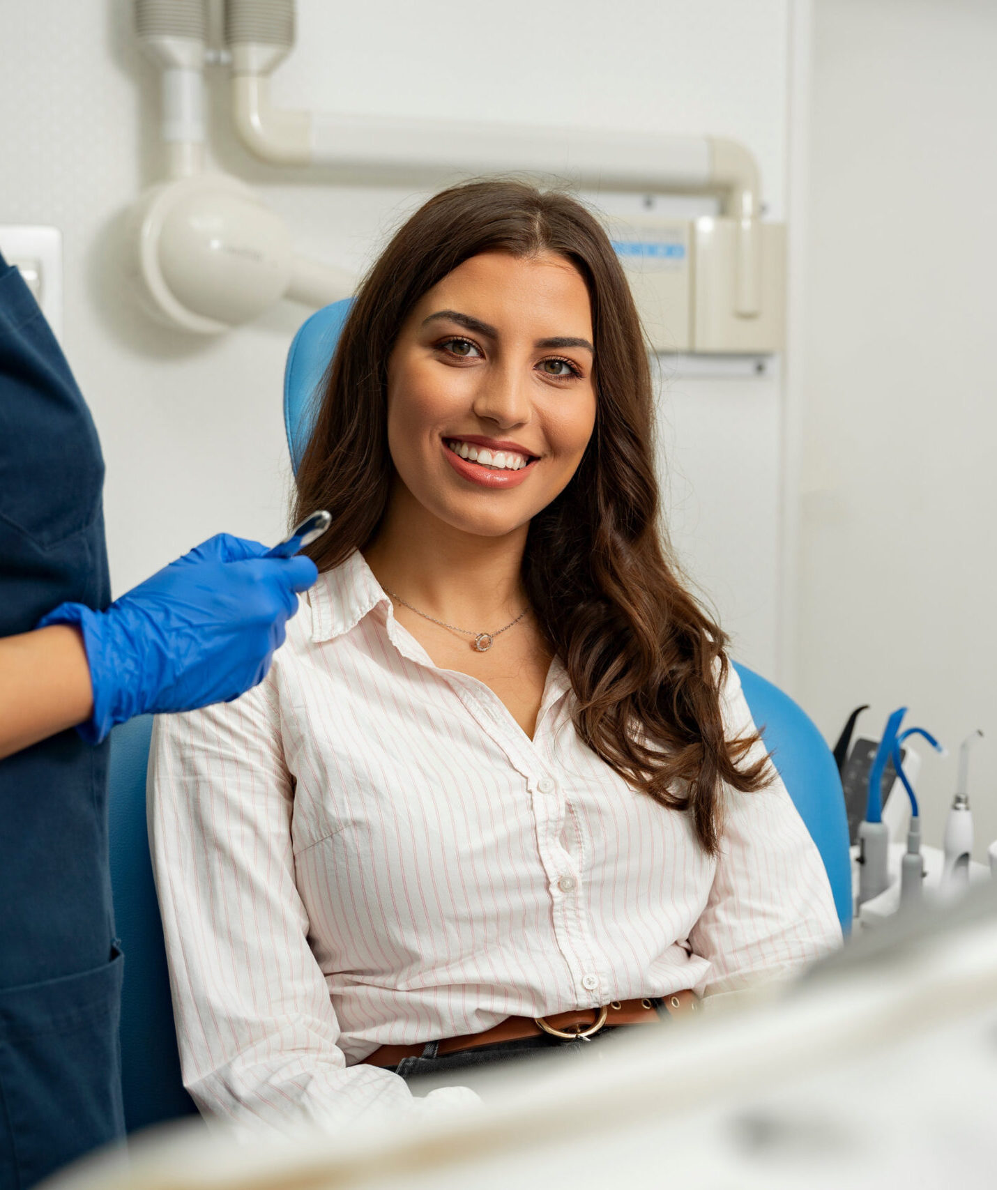 Satisfied patient sitting in dentist chair. Gorgeous young woman in dental clinic smiling from a chair next to dentist