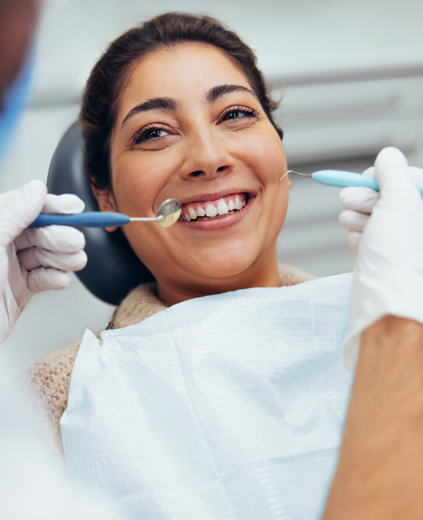 Over the shoulder view of a dental doctor treating female patient. Female having routine dental checkup at dentist.
