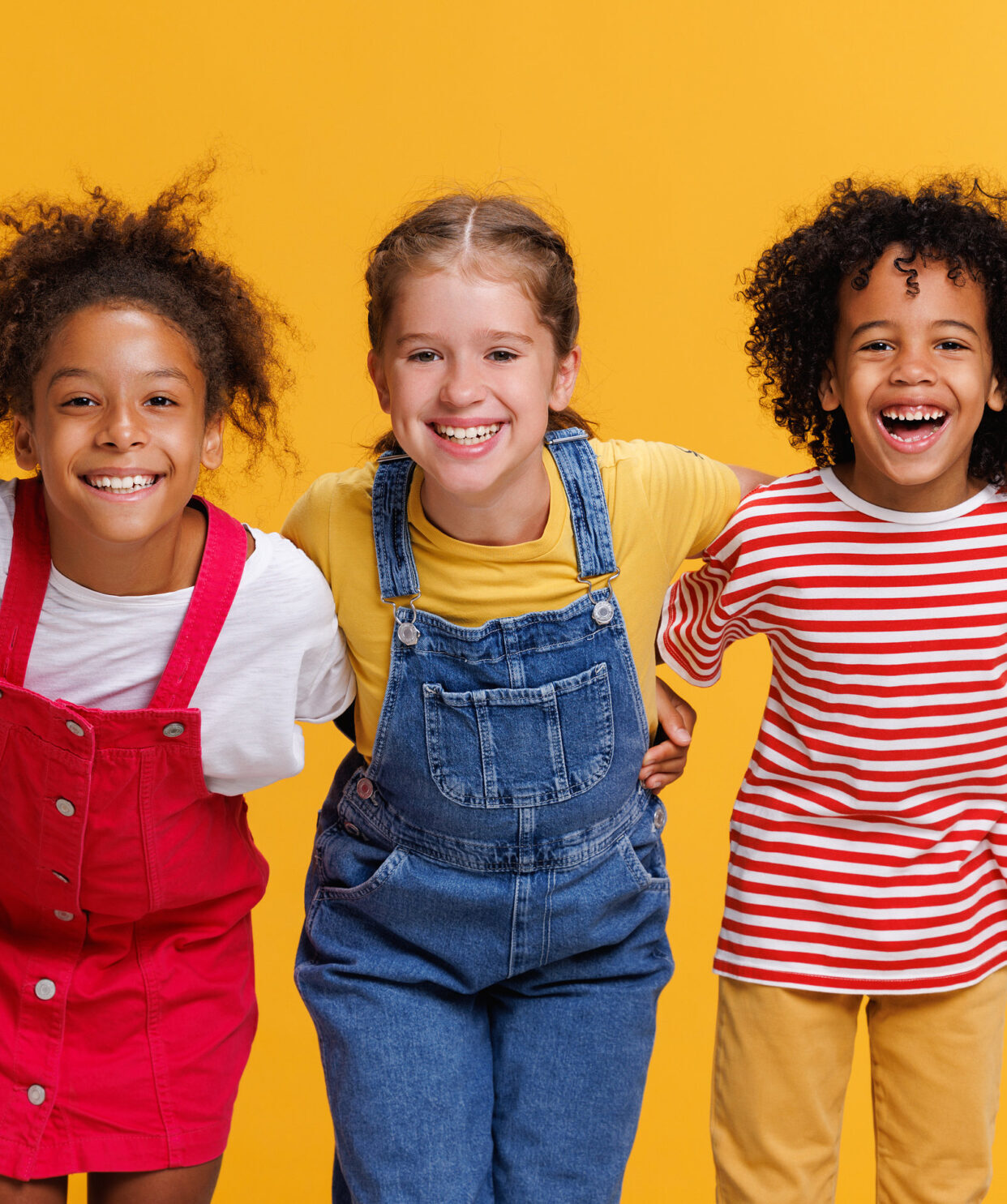 Group of cheerful happy multinational children on a colored yellow background