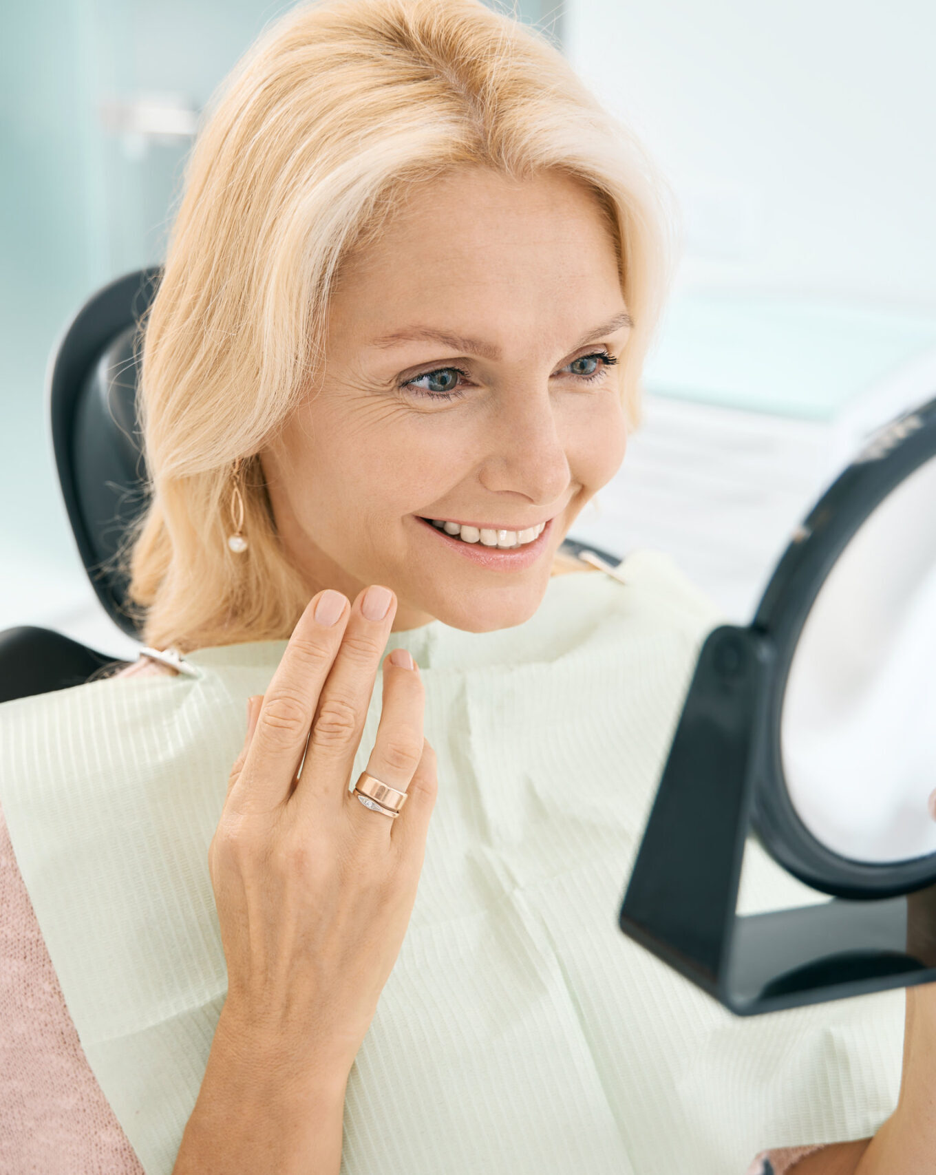 Close up portrait of pretty Caucasian female enjoying her beautiful smile after the dentistry treatment in medicine center
