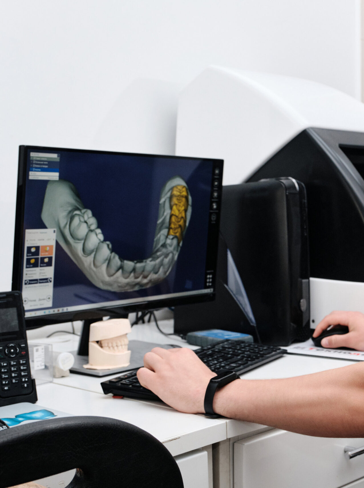 Dental technician working with a computer in a laboratory. 3D modeling of the crown in the dental lab. Workplace dental technician.