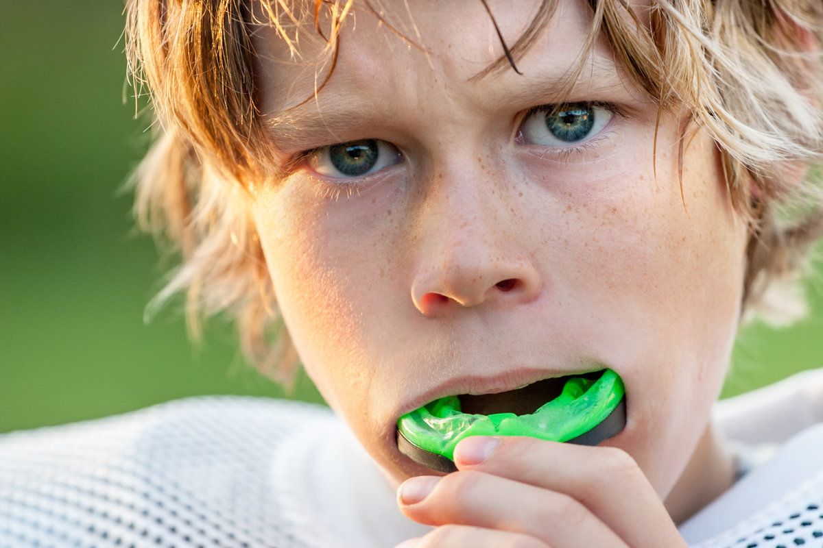 Boy with green mouthguard, intense expression