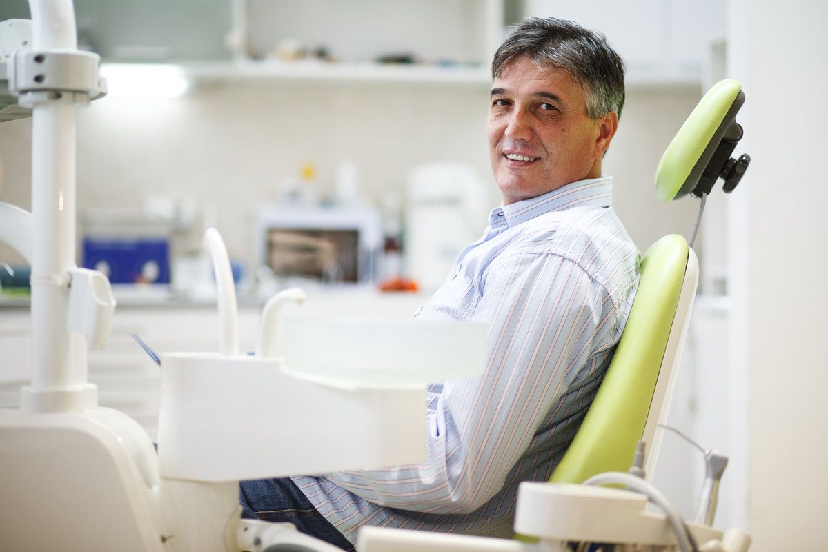 Smiling man in dental clinic chair.