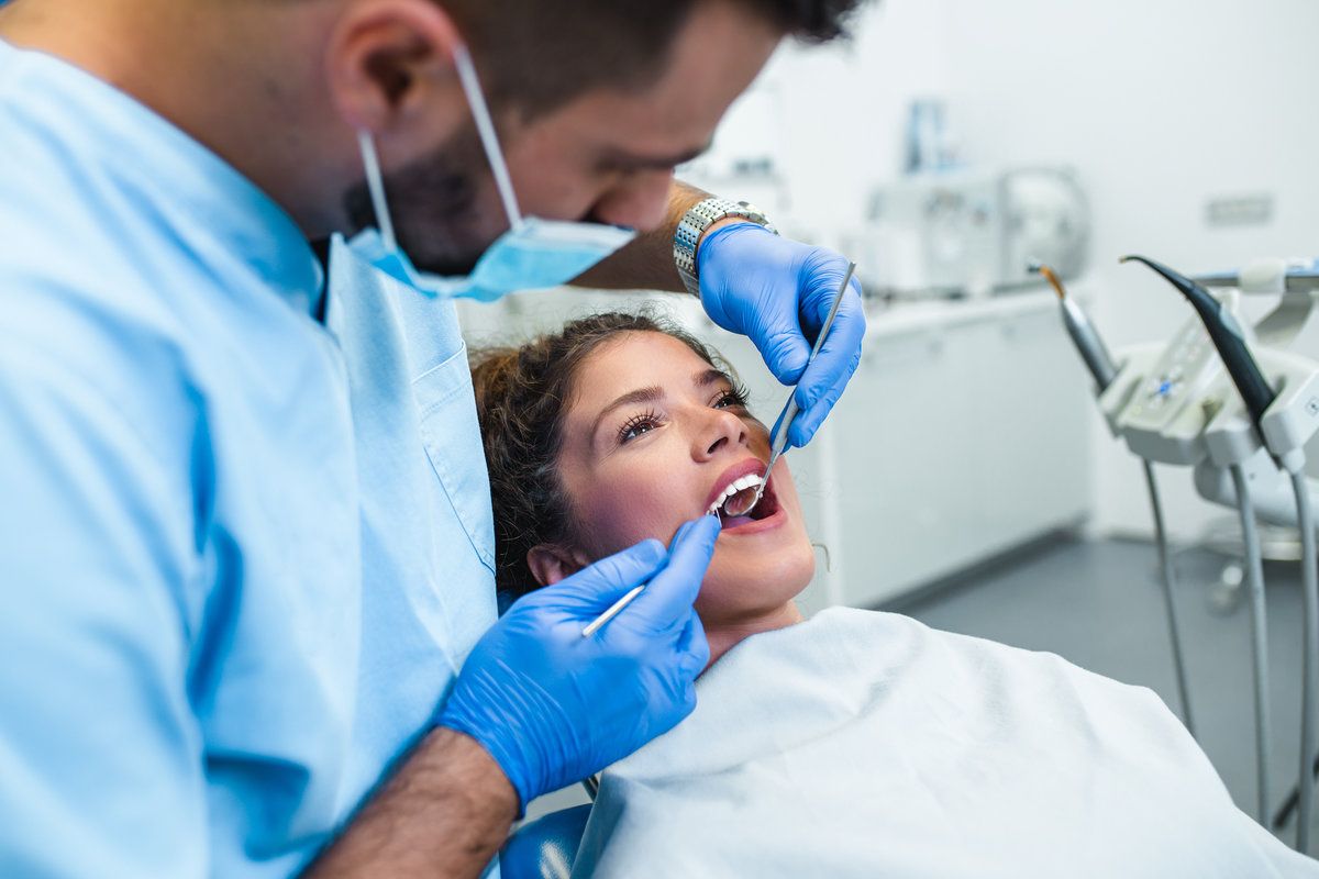 Dentist examining patient's teeth carefully.