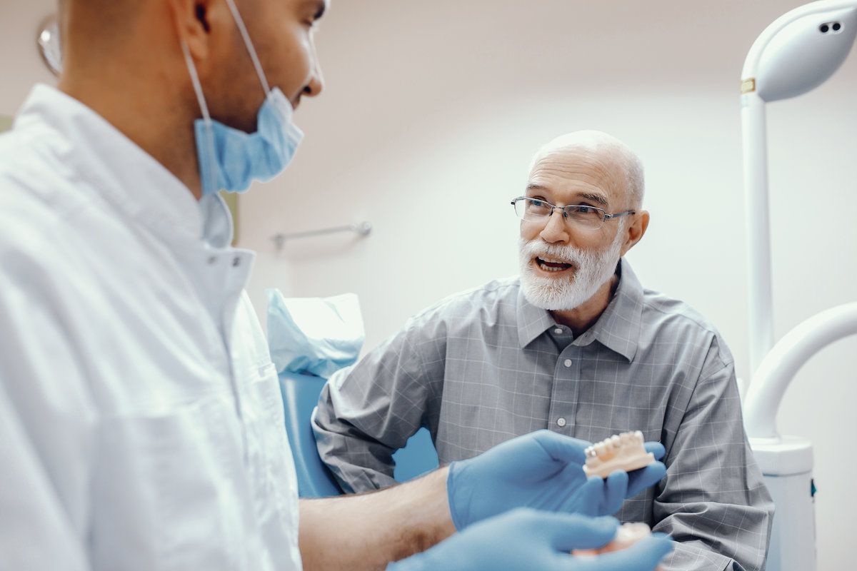 Dentist showing dentures to patient.