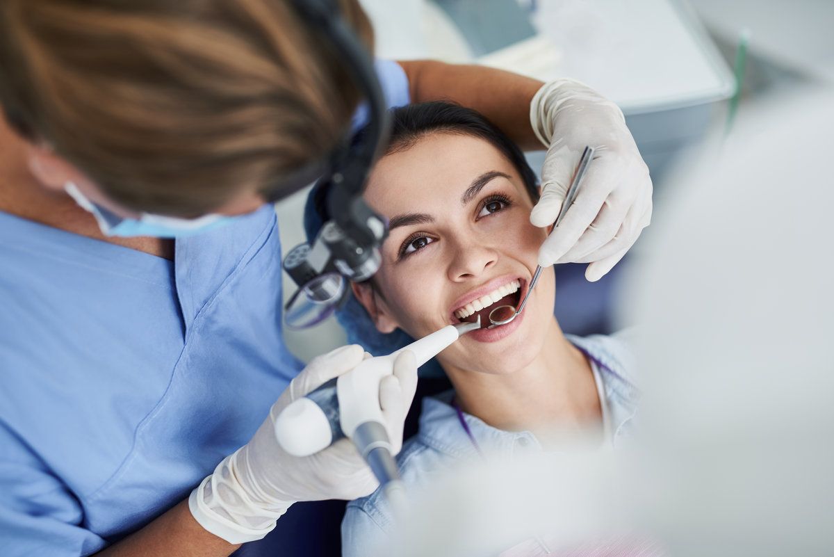 Dentist examining patient’s teeth smiling
