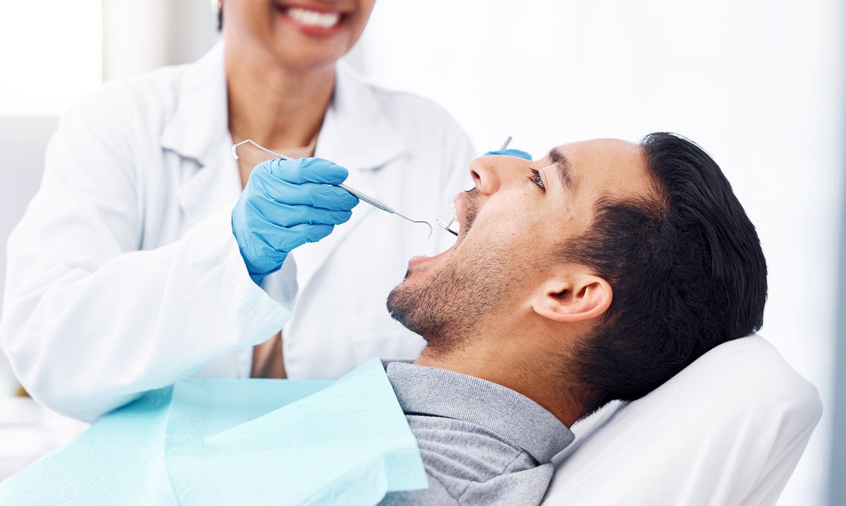 Dentist examining patient's open mouth.